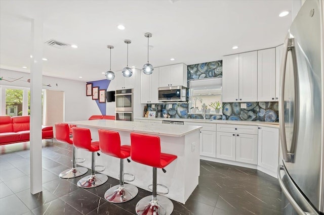 740 Eagle Dr, North Woodmere, NY 11581 - kitchen featuring stainless steel appliances, a kitchen island, light countertops, white cabinetry, and decorative backsplash