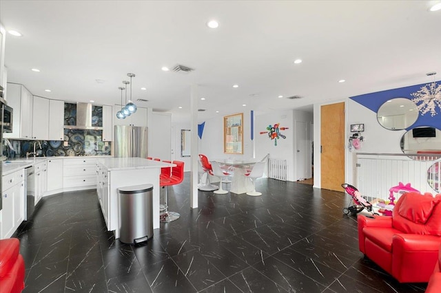 740 Eagle Dr, North Woodmere, NY 11581 - kitchen featuring appliances with stainless steel finishes, a kitchen island, light countertops, white cabinets, and backsplash