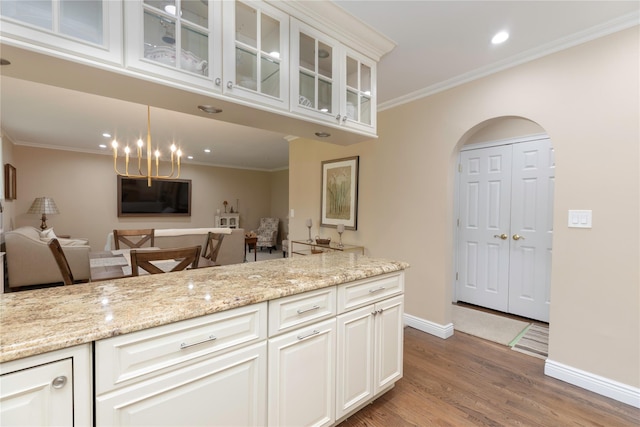 18 Channing Pl Unit 2R, Eastchester, NY 10709 - kitchen with wood finished floors, arched walkways, light stone counters, glass insert cabinets, and a chandelier