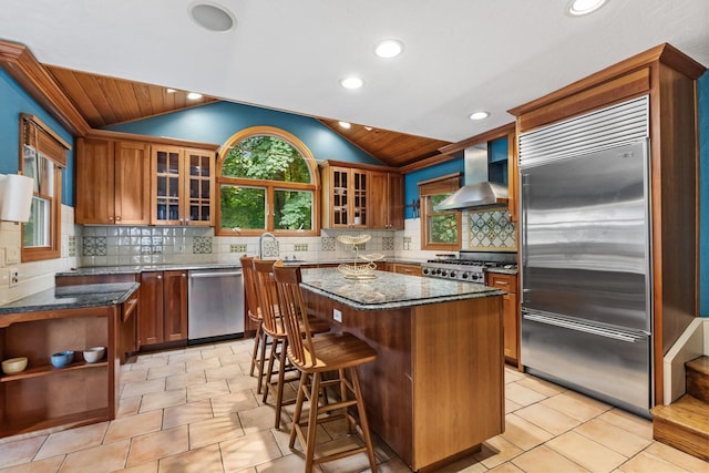 100 Norman Rd, New Rochelle, NY 10804 - kitchen with appliances with stainless steel finishes, wall chimney range hood, vaulted ceiling, dark stone counters, and wooden ceiling