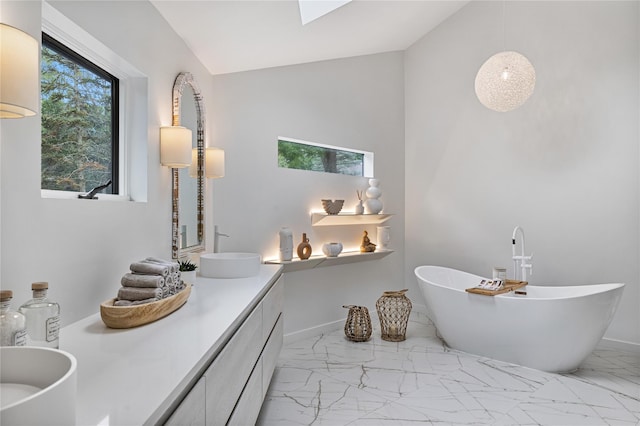 12 Zeck Ct, Suffern, NY 10901 - bathroom featuring double vanity, marble finish flooring, a freestanding tub, vaulted ceiling, and a skylight