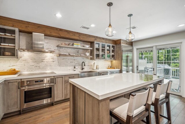 10 Pond View Ct Unit 10, Jericho, NY 11753 - kitchen with appliances with stainless steel finishes, wall chimney exhaust hood, tasteful backsplash, a kitchen breakfast bar, and light countertops