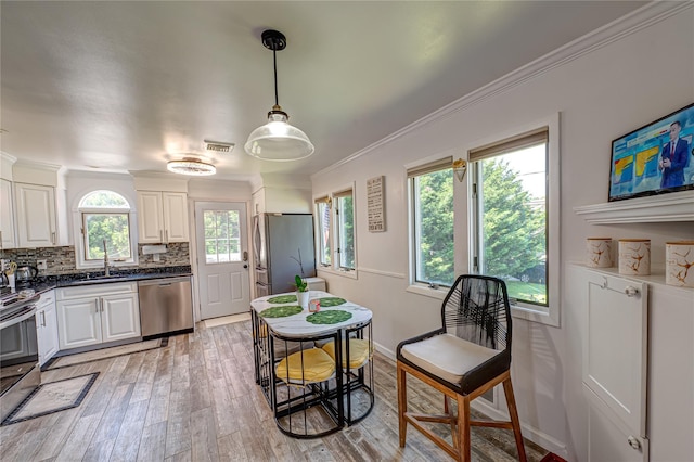 105 Graywood Ct, West Islip, NY 11795 - kitchen with stainless steel appliances, white cabinetry, light wood finished floors, ornamental molding, and decorative backsplash