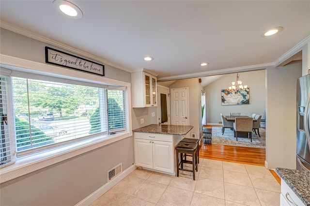 163 W 24th St, Deer Park, NY 11729 - kitchen featuring crown molding, a chandelier, a peninsula, glass insert cabinets, and a kitchen bar
