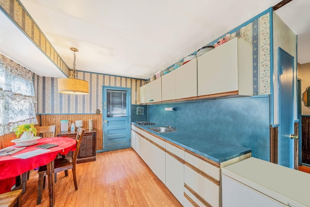 35 13th St, Bohemia, NY 11716 - kitchen with wallpapered walls, light wood-style floors, wainscoting, white cabinetry, and pendant lighting