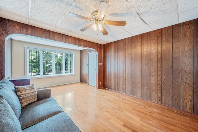 66-13 73rd Pl, Middle Village, NY 11379 - living area with arched walkways, wooden walls, wood finished floors, ceiling fan, and a drop ceiling