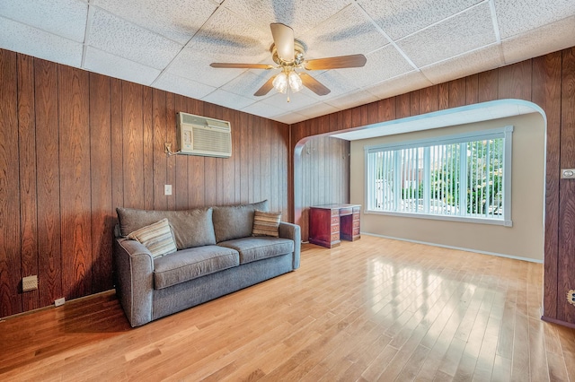 66-13 73rd Pl, Middle Village, NY 11379 - living area with arched walkways, a wall unit AC, wooden walls, a ceiling fan, and wood finished floors