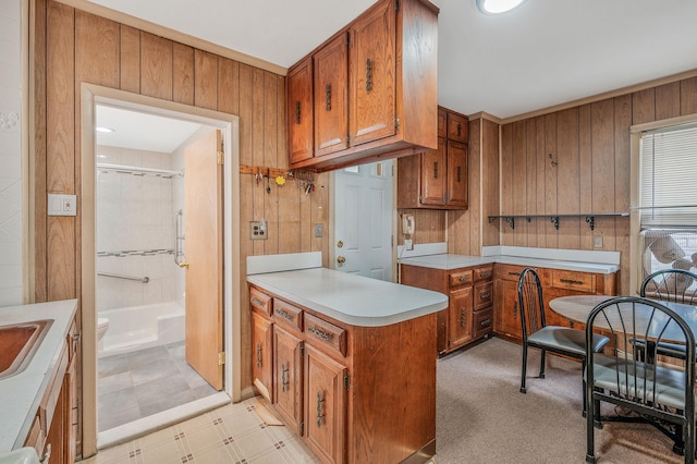 66-13 73rd Pl, Middle Village, NY 11379 - kitchen with brown cabinets, light countertops, a peninsula, and wood walls