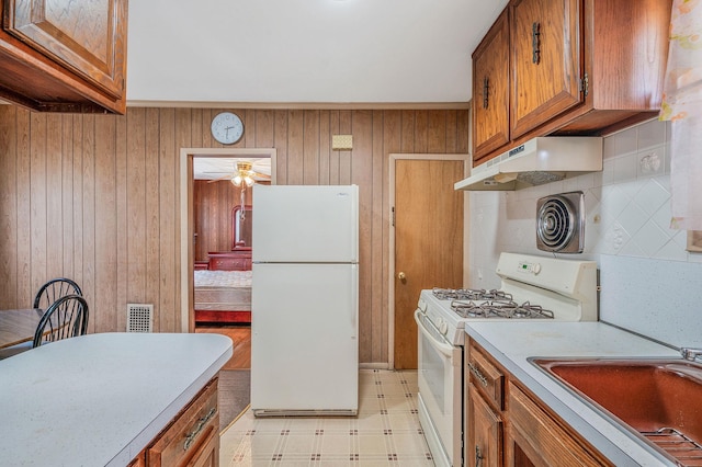 66-13 73rd Pl, Middle Village, NY 11379 - kitchen with white appliances, under cabinet range hood, brown cabinets, light flooring, and wood walls