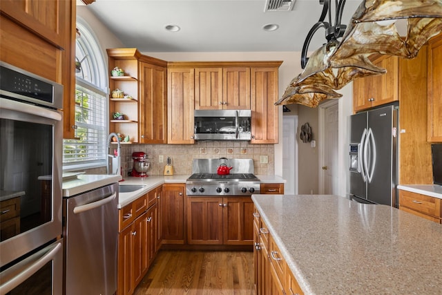 248 Delaware Ave, Island Park, NY 11558 - kitchen with appliances with stainless steel finishes, brown cabinetry, open shelves, wood finished floors, and backsplash