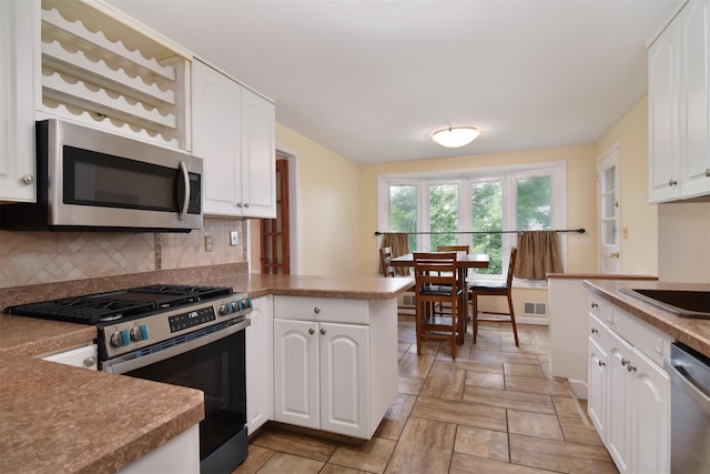 38 Balmoral Cres, White Plains, NY 10607 - kitchen featuring appliances with stainless steel finishes, decorative backsplash, a peninsula, and white cabinets