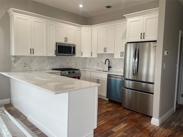 62 Clark St, Long Beach, NY 11561 - kitchen with appliances with stainless steel finishes, dark wood finished floors, a peninsula, white cabinetry, and recessed lighting