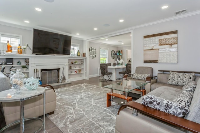 1 Howland Rd, East Rockaway, NY 11518 - living area featuring crown molding, wood finished floors, plenty of natural light, recessed lighting, and a glass covered fireplace