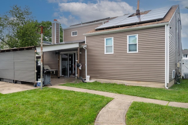 114 Cone Ave, Central Islip, NY 11722 - rear view of house with solar panels, a yard, and a chimney
