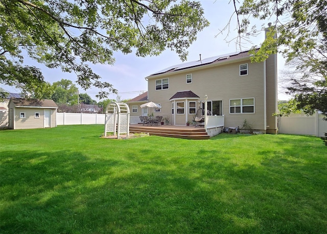 54 Gatelot Ave, Lake Ronkonkoma, NY 11779 - rear view of house featuring a fenced backyard, a chimney, a wooden deck, and roof mounted solar panels