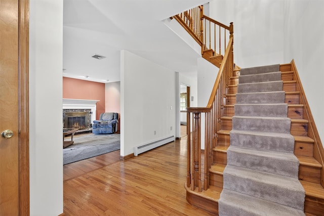 561 Toleman Rd, Rock Tavern, NY 12575 - stairway featuring baseboard heating, wood finished floors, and a stone fireplace
