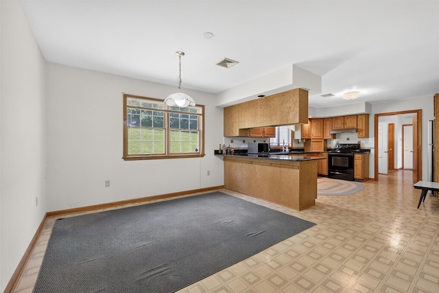 561 Toleman Rd, Rock Tavern, NY 12575 - kitchen featuring electric range, dark countertops, a peninsula, brown cabinetry, and under cabinet range hood