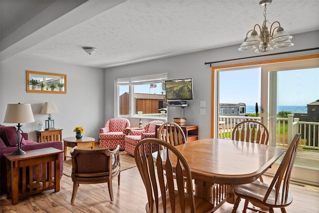 100 Deforest Rd Unit 701, Montauk, NY 11954 - dining space featuring a chandelier, light wood-style floors, and a textured ceiling