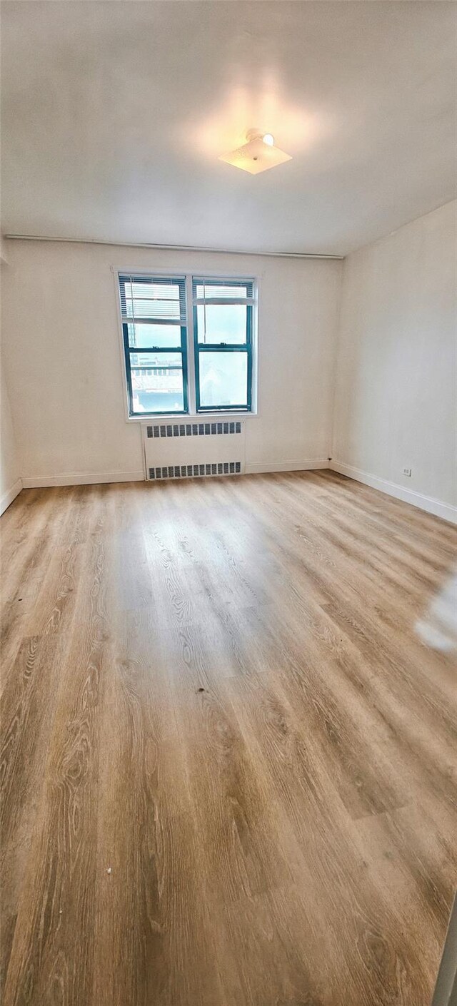 6615 Wetherole St Unit D12, Rego Park, NY 11374 - spare room with radiator heating unit and light wood-type flooring