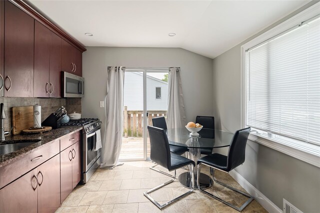 22 Pomper Dr, East Northport, NY 11731 - kitchen with appliances with stainless steel finishes, backsplash, lofted ceiling, dark stone countertops, and light tile patterned floors