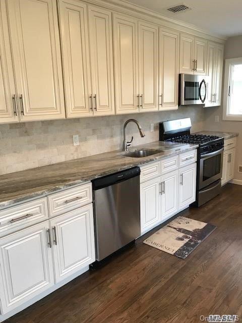 5 Fruitwood Ln, Commack, NY 11725 - kitchen with stainless steel appliances, dark wood-style flooring, decorative backsplash, stone countertops, and white cabinetry
