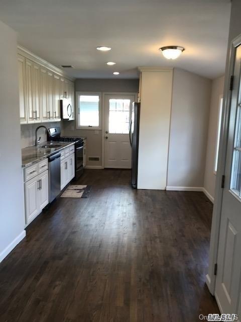 5 Fruitwood Ln, Commack, NY 11725 - kitchen with dishwasher, gas range oven, dark wood-type flooring, freestanding refrigerator, and stone countertops