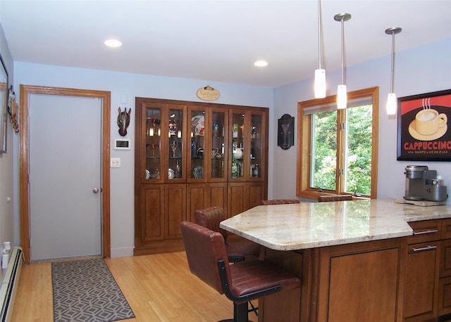 1778 Spur Dr S, Islip, NY 11751 - kitchen with baseboard heating, light wood-style flooring, light stone counters, brown cabinets, and hanging light fixtures