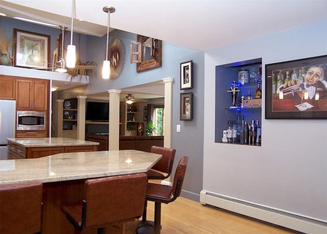 1778 Spur Dr S, Islip, NY 11751 - kitchen with a baseboard heating unit, ornate columns, appliances with stainless steel finishes, brown cabinetry, and light stone countertops