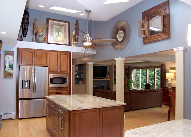 1778 Spur Dr S, Islip, NY 11751 - kitchen featuring stainless steel appliances, brown cabinetry, ornate columns, light wood-style flooring, and a towering ceiling