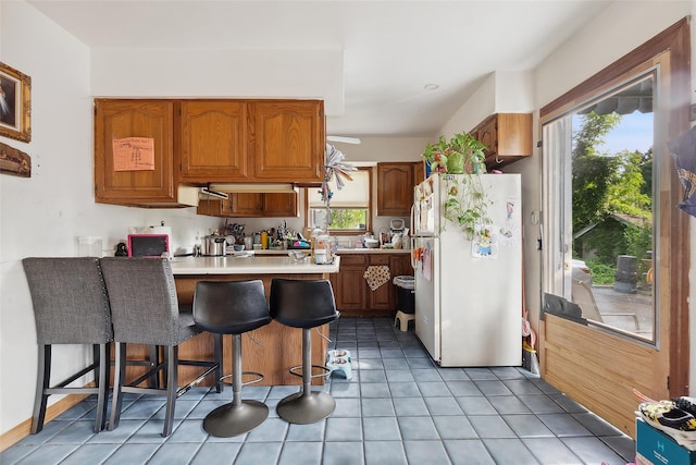 1222 Brook St, Peekskill, NY 10566 - kitchen featuring freestanding refrigerator, a peninsula, light countertops, and brown cabinetry
