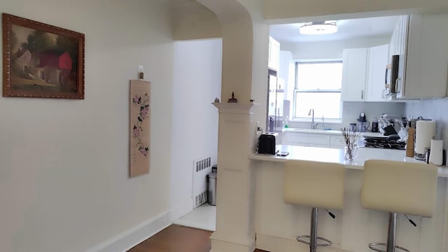 67-38 108st St Unit A53, Forest Hills, NY 11375 - kitchen with a breakfast bar, a peninsula, white cabinets, stainless steel microwave, and light countertops