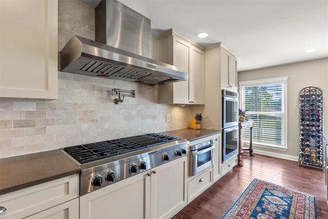 16 Dyke Rd, Setauket, NY 11733 - kitchen featuring wall chimney exhaust hood, dark countertops, stainless steel appliances, dark wood-style flooring, and tasteful backsplash
