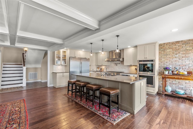 16 Dyke Rd, Setauket, NY 11733 - kitchen featuring stainless steel appliances, wall chimney range hood, a breakfast bar, backsplash, and a kitchen island with sink