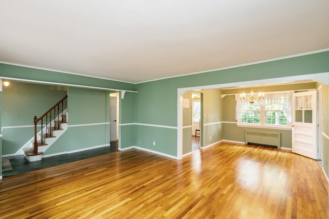 76 Roebling Pl E, Northport, NY 11731 - spare room with radiator, a chandelier, wood finished floors, ornamental molding, and stairs