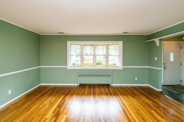 76 Roebling Pl E, Northport, NY 11731 - empty room featuring radiator heating unit, healthy amount of natural light, crown molding, and wood finished floors