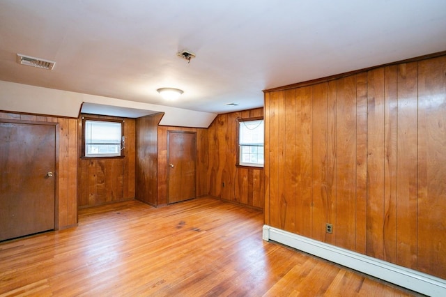 76 Roebling Pl E, Northport, NY 11731 - unfurnished bedroom with baseboard heating, light wood-style floors, and wooden walls