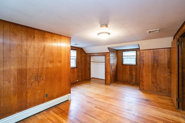 76 Roebling Pl E, Northport, NY 11731 - unfurnished bedroom with baseboard heating, light wood finished floors, wooden walls, multiple windows, and vaulted ceiling
