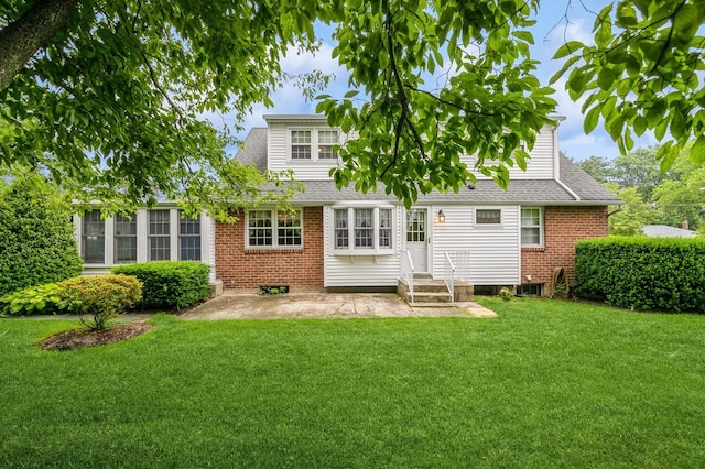 76 Roebling Pl E, Northport, NY 11731 - rear view of property featuring brick siding, roof with shingles, a yard, and entry steps