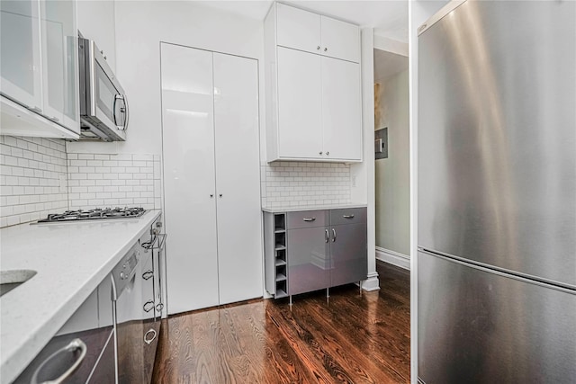 237 Eldridge St Unit 3 & 4, New York Manhattan, NY 10002 - kitchen with stainless steel appliances, dark wood-type flooring, decorative backsplash, white cabinetry, and modern cabinets