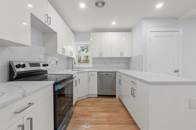 22019 135th Ave, Addisleigh Park, NY 11413 - kitchen featuring stainless steel appliances, a peninsula, light stone countertops, white cabinets, and light wood finished floors