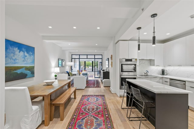 100 Pondfield Rd Unit 2B, Bronxville, NY 10708 - kitchen featuring appliances with stainless steel finishes, a breakfast bar, light wood-type flooring, tasteful backsplash, and a kitchen island