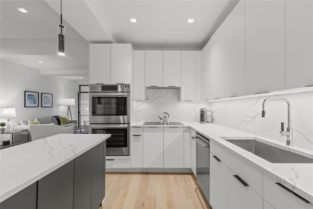 100 Pondfield Rd Unit 2B, Bronxville, NY 10708 - kitchen featuring stainless steel appliances, white cabinets, light stone counters, tasteful backsplash, and light wood-type flooring
