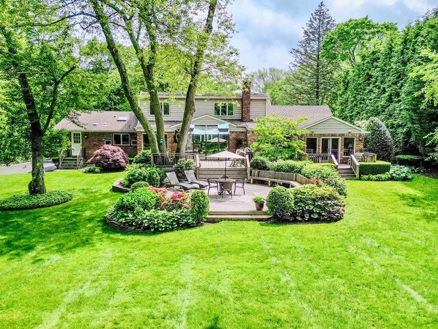 14 Pine Dr, Woodbury, NY 11797 - rear view of property with a deck, a chimney, brick siding, a patio, and a lawn