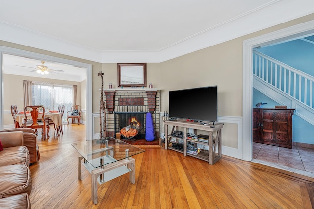 42 S Montague St, Valley Stream, NY 11580 - living area featuring wood finished floors, a brick fireplace, a wainscoted wall, stairs, and ceiling fan