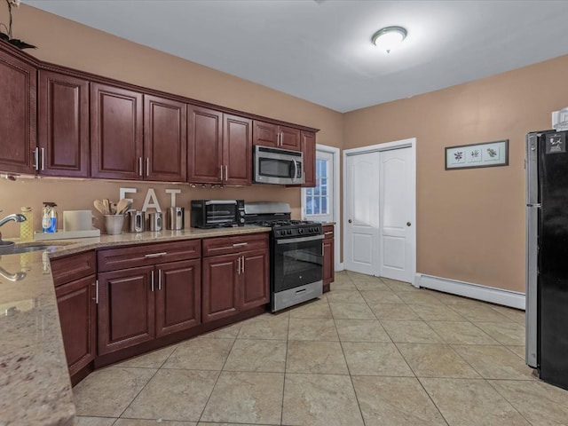 2677 Heath Ave, Bronx, NY 10463 - kitchen with stainless steel appliances, a baseboard heating unit, light stone countertops, and light tile patterned floors
