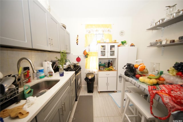 40-45 99th St, Corona, NY 11368 - kitchen with stainless steel gas range oven, gray cabinetry, light countertops, decorative backsplash, and open shelves
