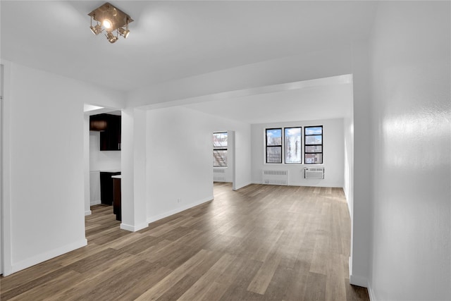 3184 Grand Unit 6D, Bronx, NY 10458 - unfurnished living room featuring radiator heating unit, a wall unit AC, and wood finished floors