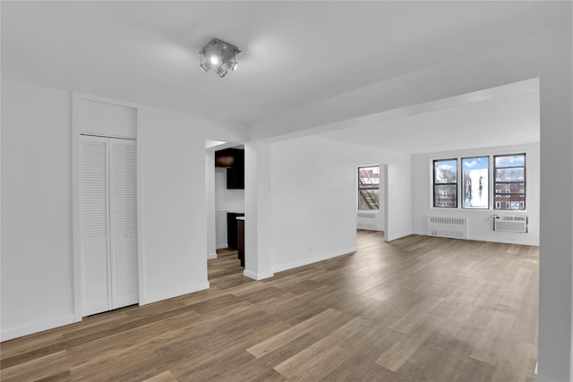 3184 Grand Unit 6D, Bronx, NY 10458 - unfurnished living room with radiator, a wall unit AC, and wood finished floors