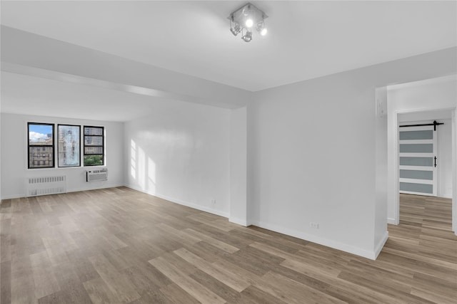 3184 Grand Unit 6D, Bronx, NY 10458 - spare room featuring radiator, wood finished floors, a barn door, and a wall unit AC