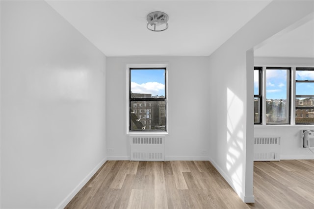 3184 Grand Unit 6D, Bronx, NY 10458 - spare room featuring radiator heating unit, wood finished floors, and healthy amount of natural light